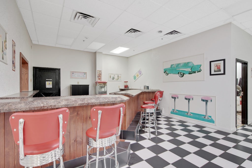 A retro-style diner with red barstools, a checkered floor, and classic vintage decor.