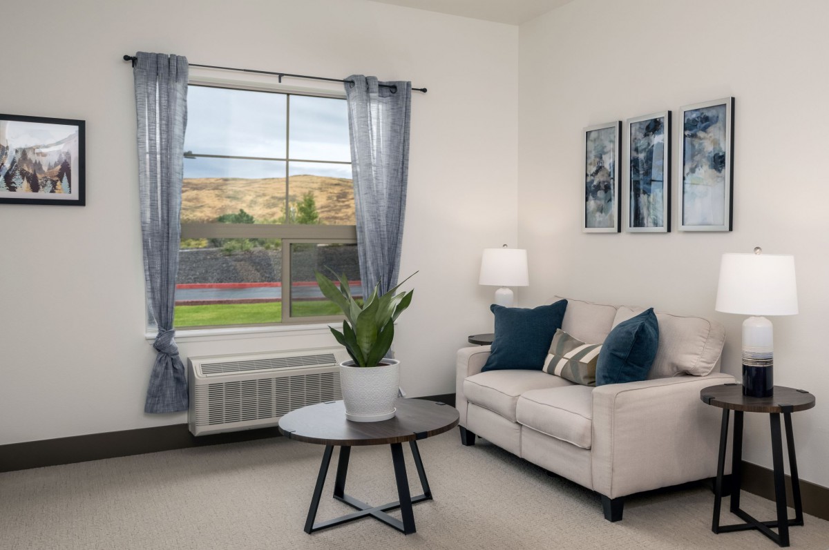 A cozy living room with a sofa, coffee table, and decorative elements including a plant and artwork.