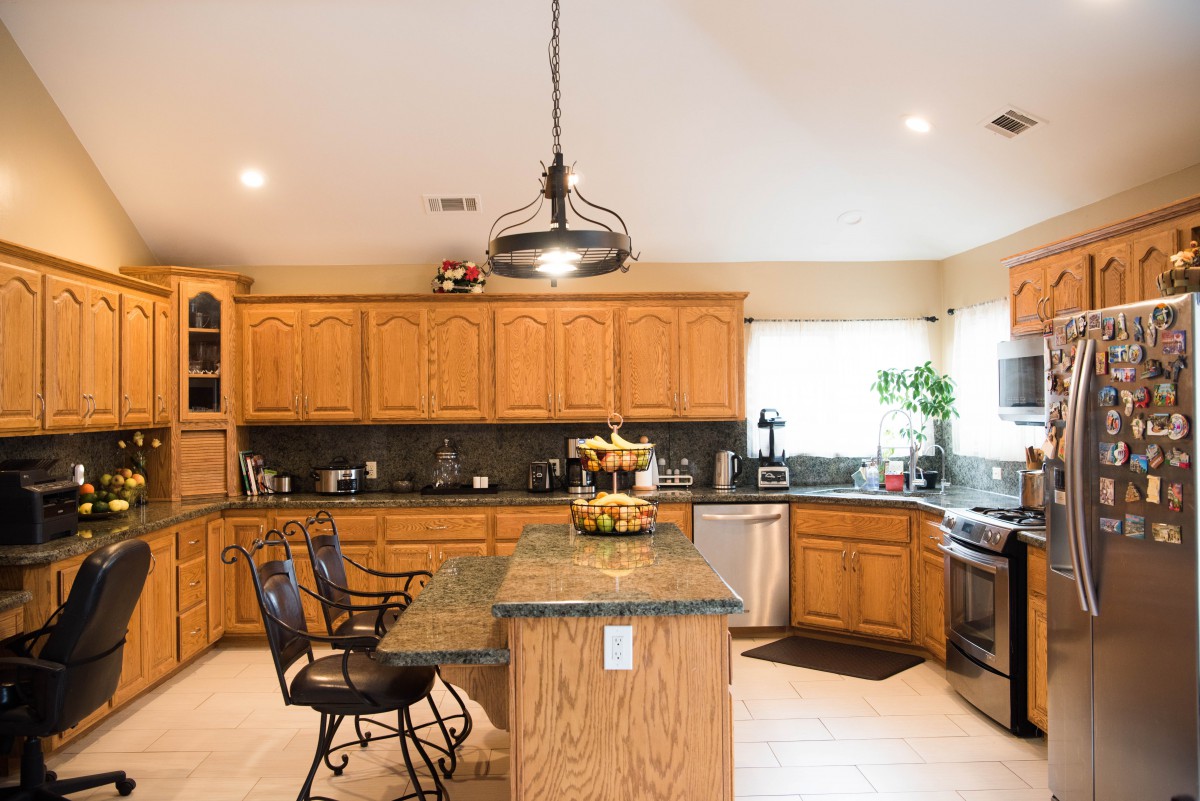 A spacious kitchen featuring wooden cabinets, an island with bar stools, and modern lighting.