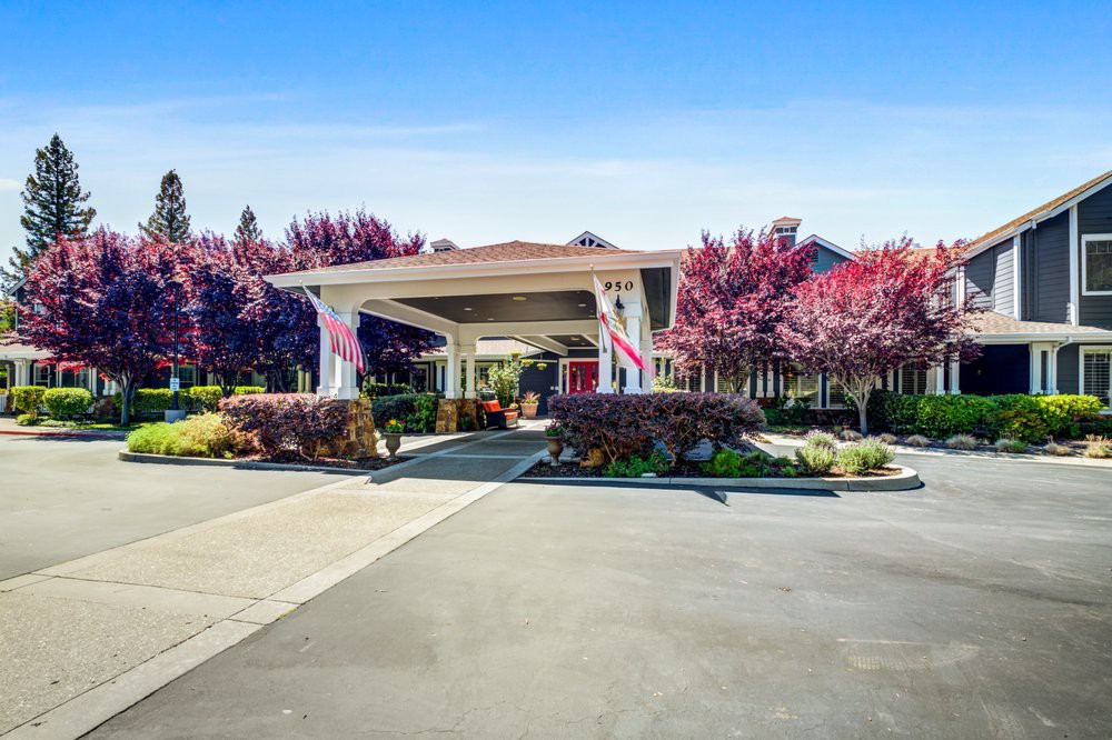 A well-landscaped building entrance with vibrant trees and a clear driveway.