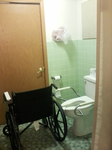 A wheelchair positioned next to a bathroom toilet, highlighting accessibility features.