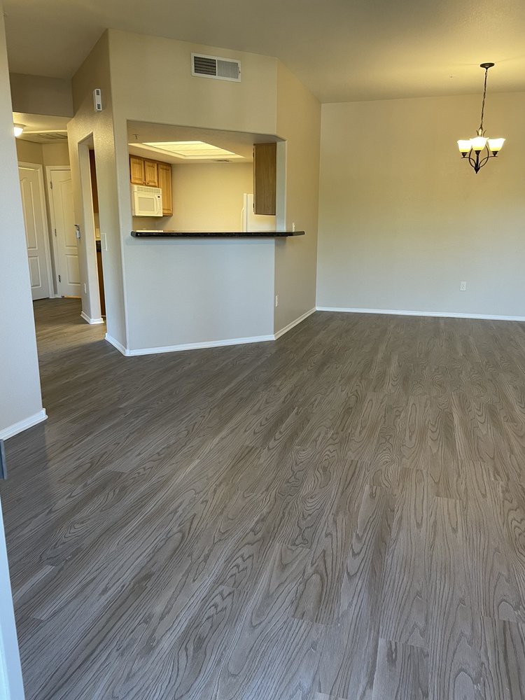 An open living and dining area with wooden flooring and a view of the kitchen.