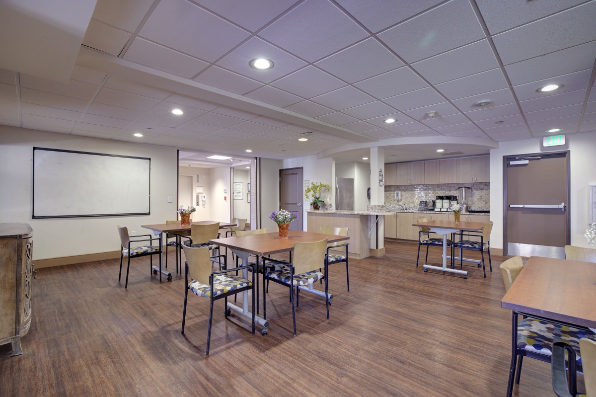 A modern interior space featuring several tables and chairs, illuminated by overhead lighting with a wooden floor setting.