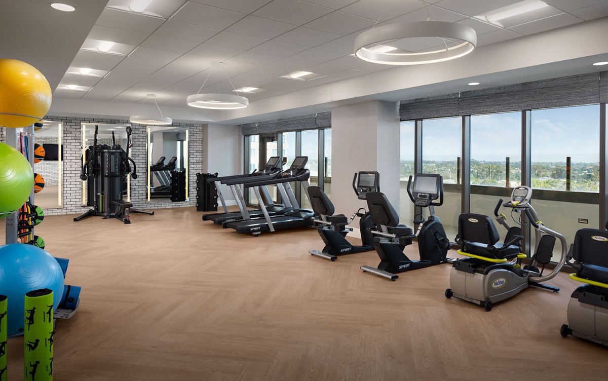 A modern gym with various fitness equipment and large windows.