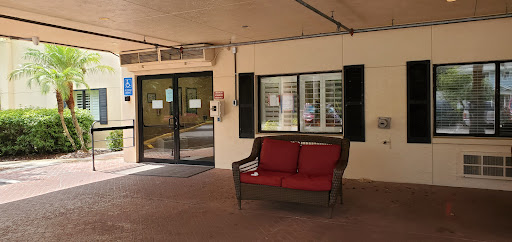 A cozy seating area outside an entrance, featuring a red couch and large windows.