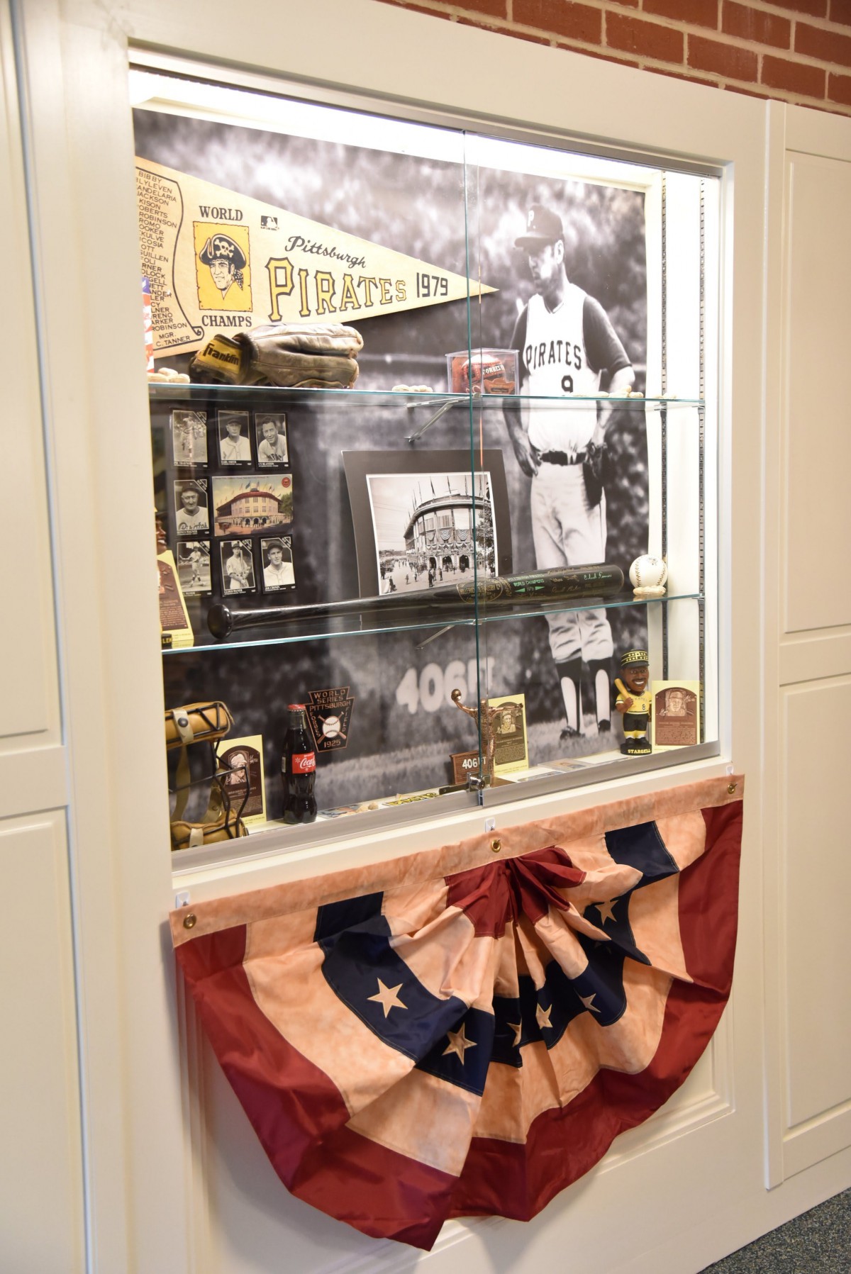 A display case showcasing baseball memorabilia related to the Pittsburgh Pirates, featuring vintage items and photographs.