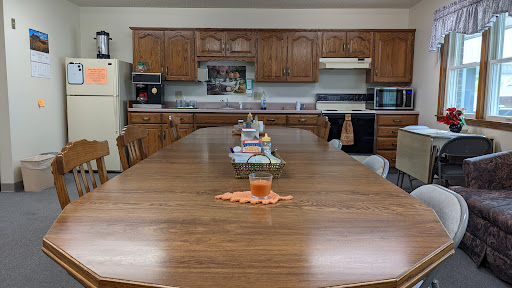 A spacious kitchen featuring a long wooden dining table and classic cabinetry.