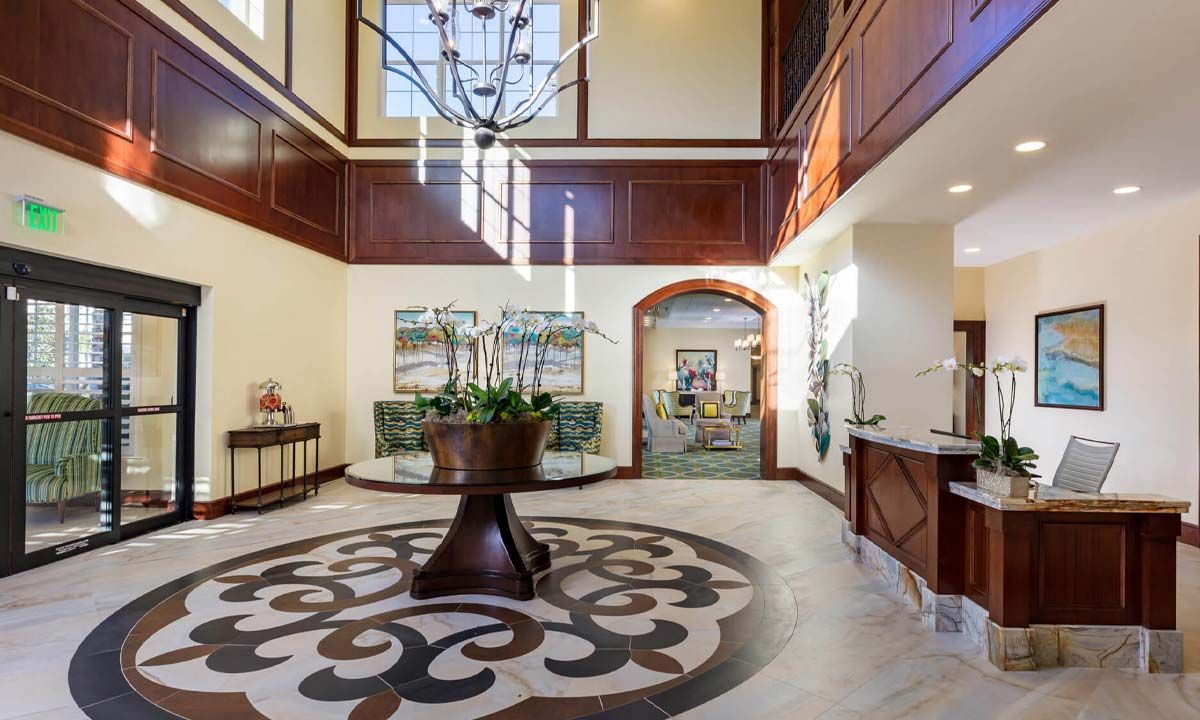 A luxurious lobby with a decorative floor design, featuring a chandelier and wood paneling.