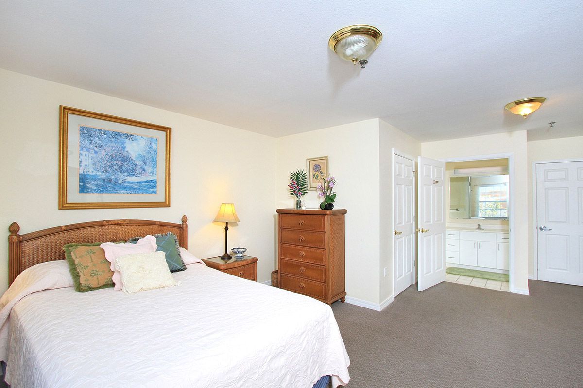 A cozy bedroom with a bed, dresser, and a view into the bathroom.