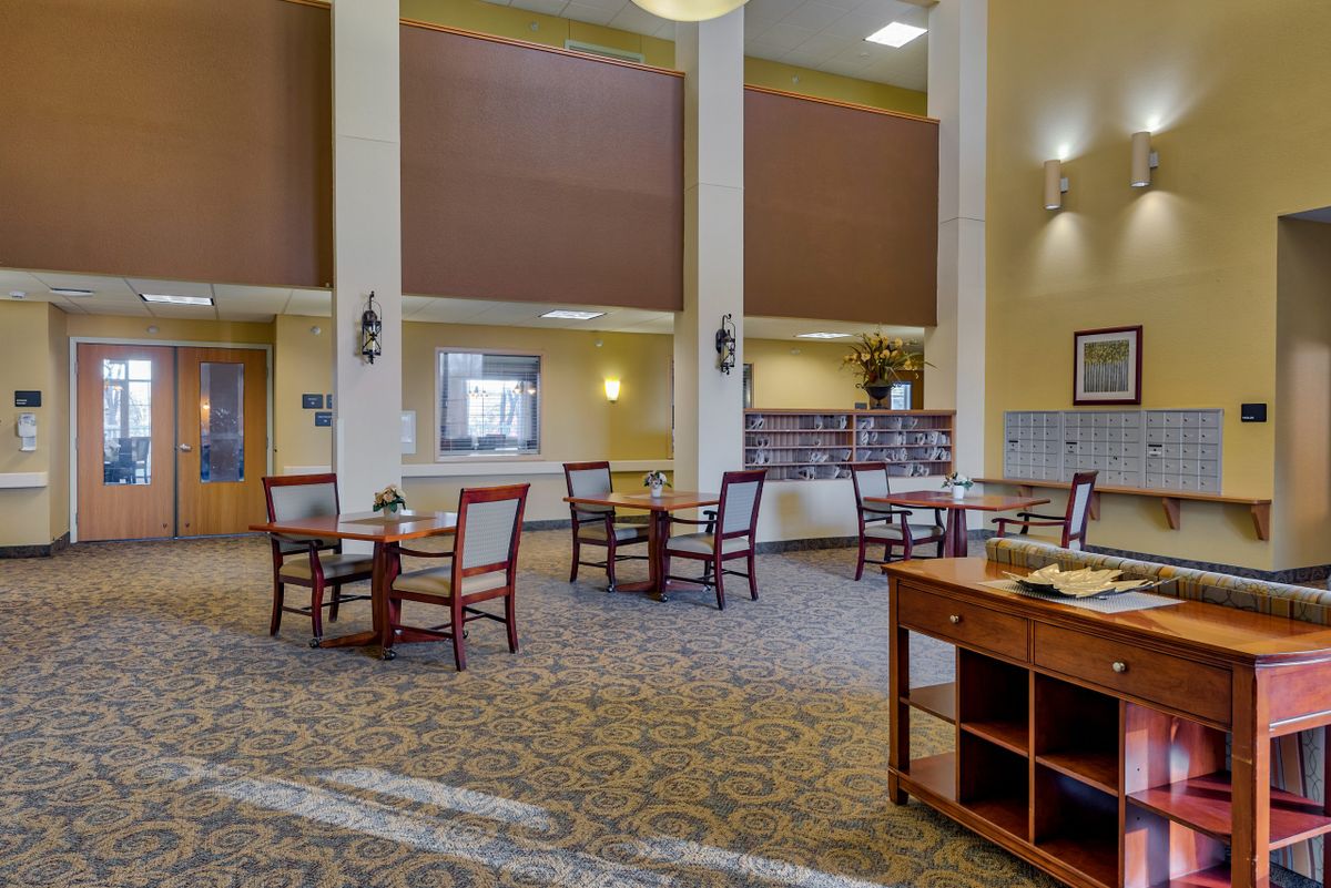 Spacious dining area with multiple tables and chairs in a well-lit, carpeted room.