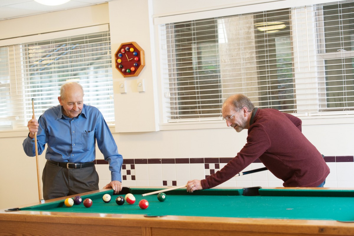 Two seniors enjoying a game of billiards indoors.