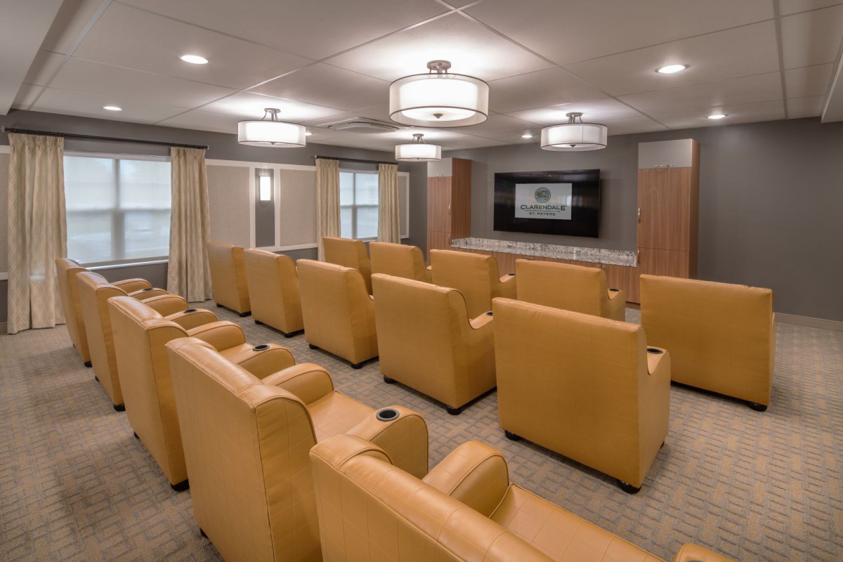 A cozy home theater with rows of comfortable recliner seating and a large projector screen.