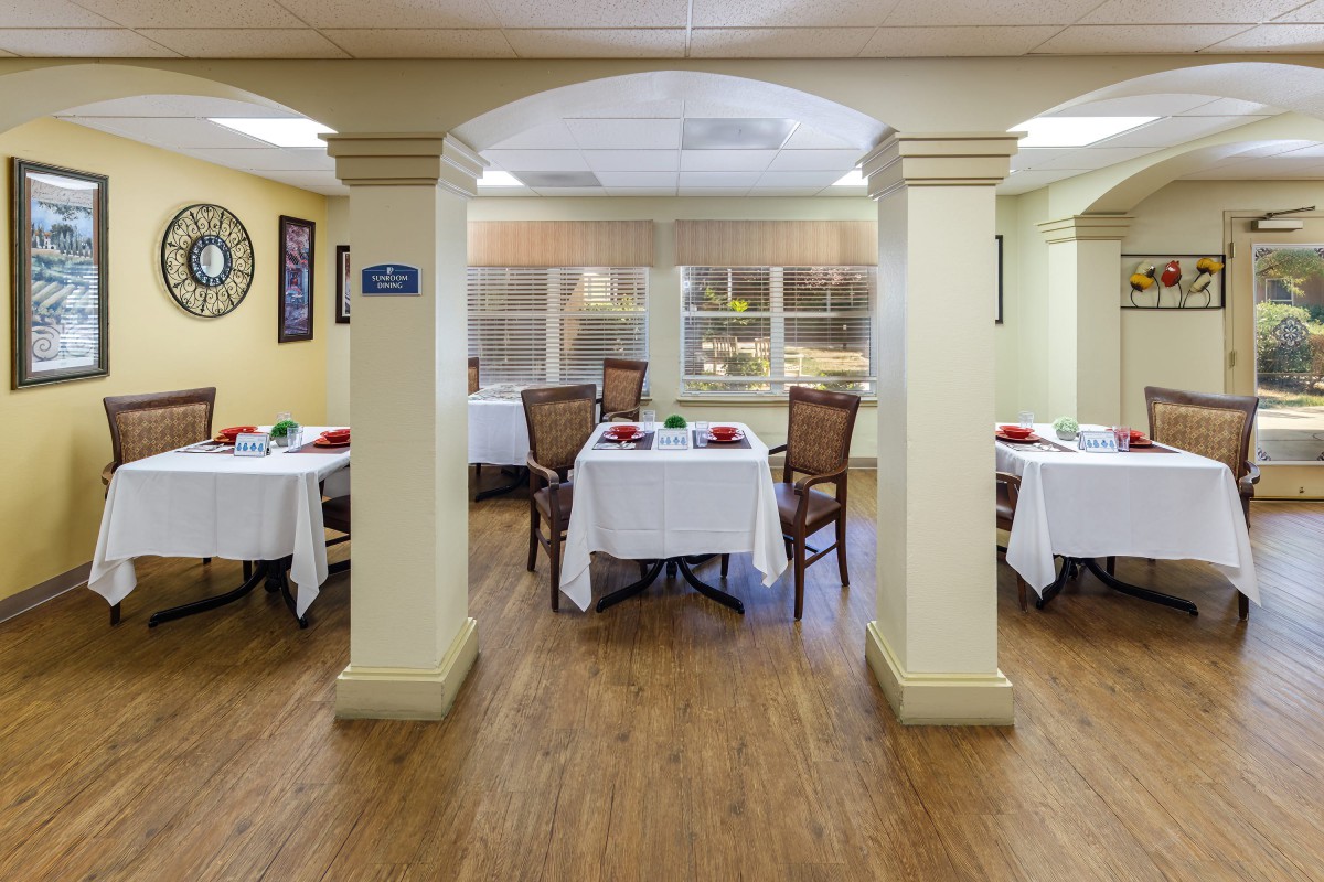An elegantly set dining area with tables and chairs in a cozy indoor setting.