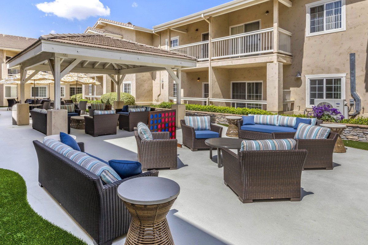 A cozy outdoor seating area in an apartment complex featuring comfortable patio furniture and a central gazebo.