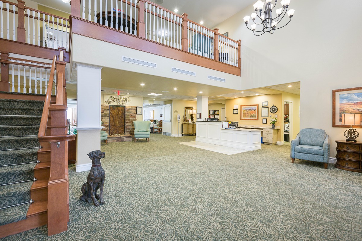 A modern lobby with a dog statue, chandelier, and reception desk in an open and inviting space.