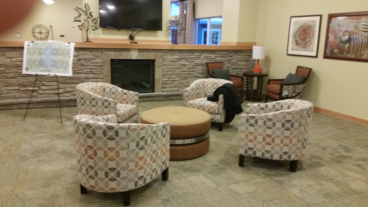 A cozy living room with a modern fireplace, patterned armchairs, and a round coffee table.