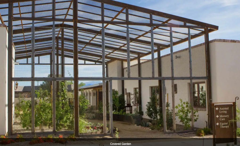 A metal framework structure adjacent to a building, surrounded by greenery.