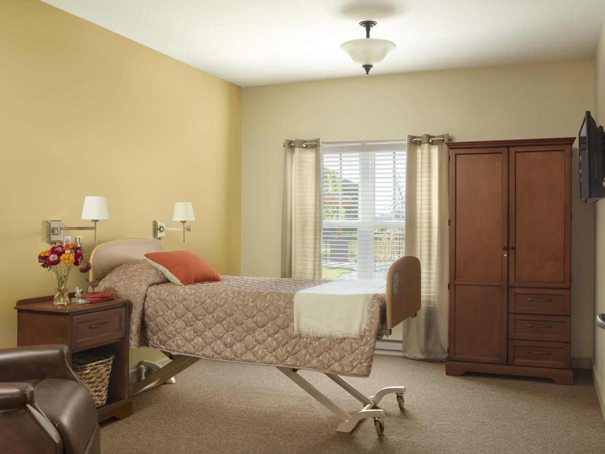 A cozy bedroom featuring a hospital bed, wooden cabinet, and soft lighting.