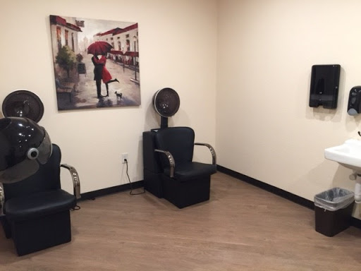 A cozy salon waiting area featuring stylish chairs and an artistic photograph.