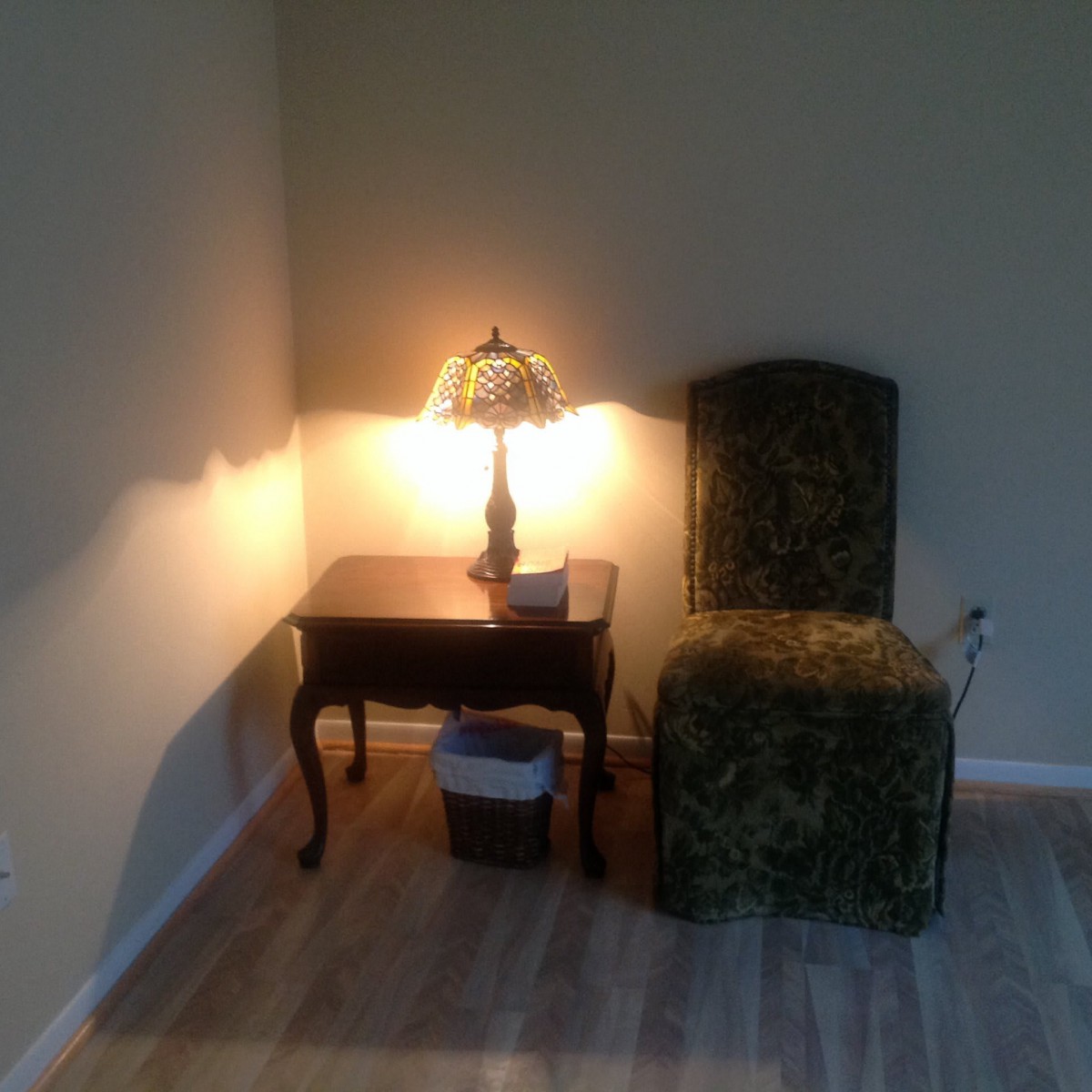 A cozy corner with a chair, table, and lamp softly illuminating the space.