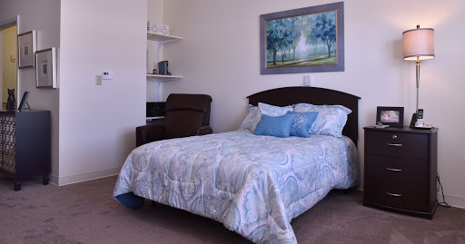 A cozy bedroom featuring a neatly made bed with decorative pillows and a framed painting on the wall.