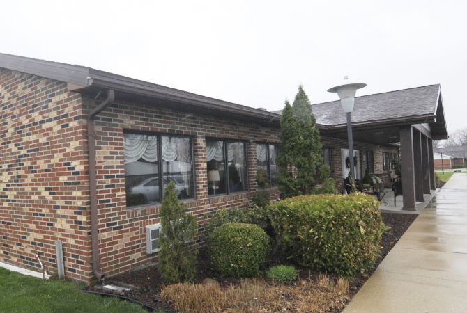 A brick building with neatly trimmed bushes and windows on a cloudy day.
