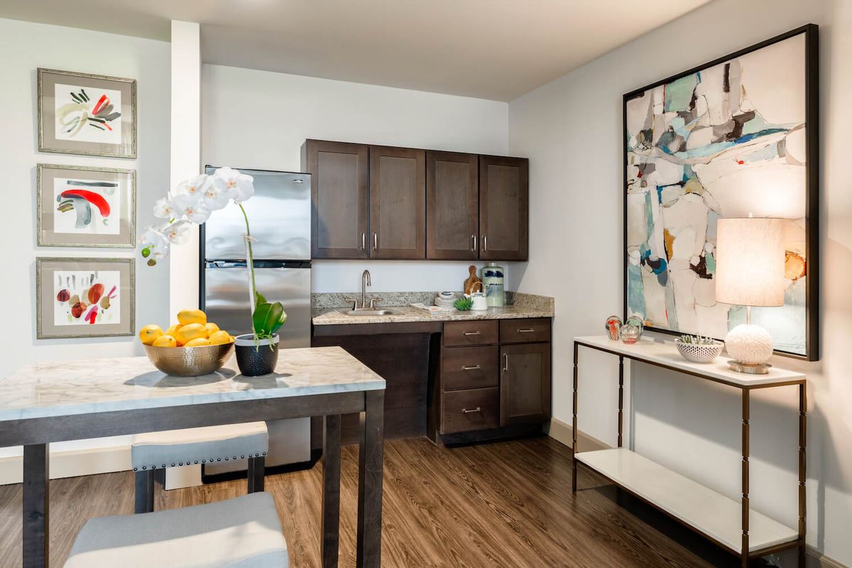 A modern kitchen with dark wood cabinets and a small dining area.