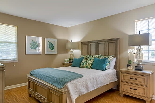 A cozy bedroom with a neatly made bed, decorative pillows, and warm lighting.