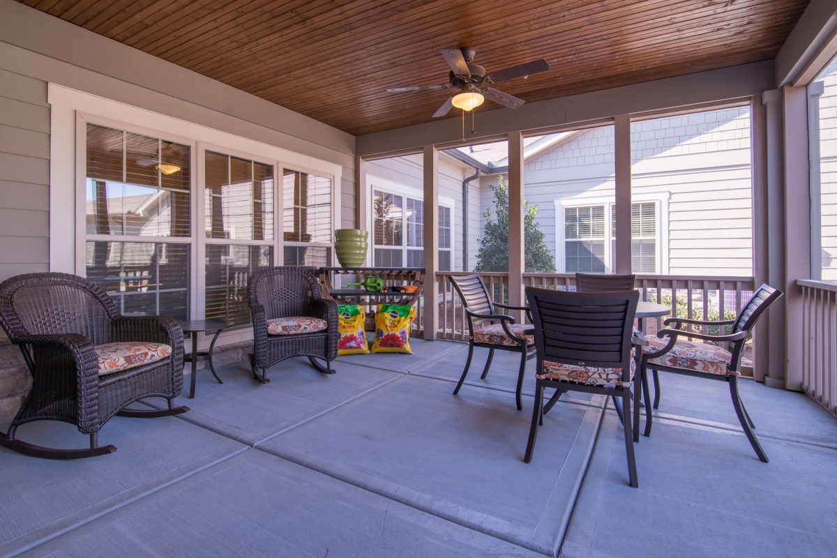 A cozy screened porch with outdoor seating and a ceiling fan.