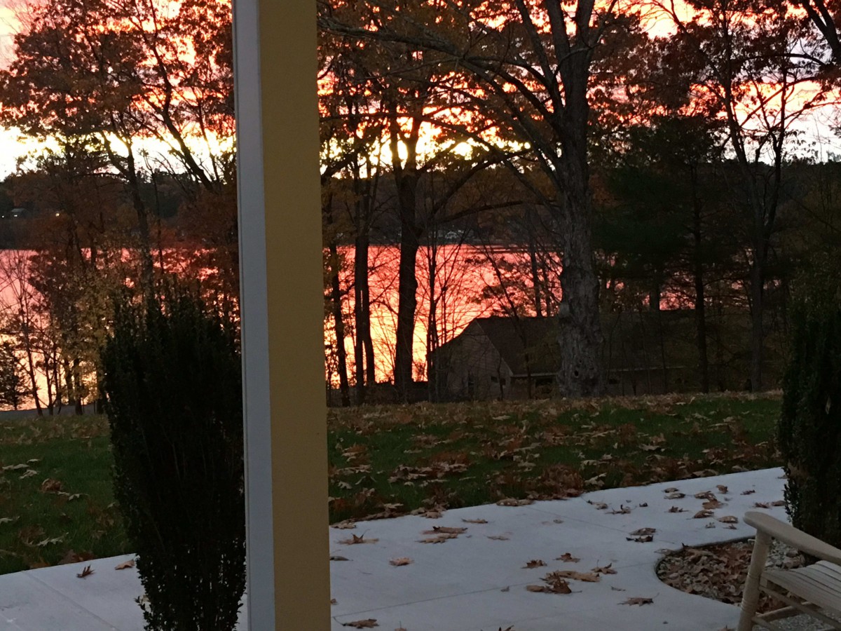 A picturesque view of a sunset reflecting off the lake, framed by trees.