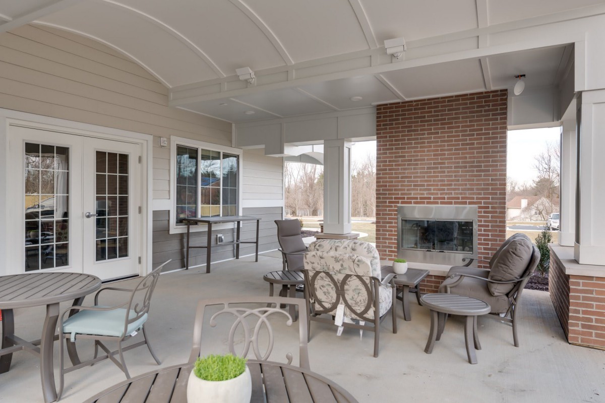 A cozy outdoor patio with comfortable seating and a brick fireplace.