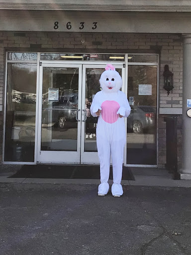 A person dressed in an Easter Bunny costume standing outside a building.