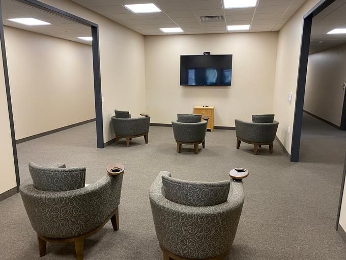 A quiet waiting room with several chairs facing a television on the wall.