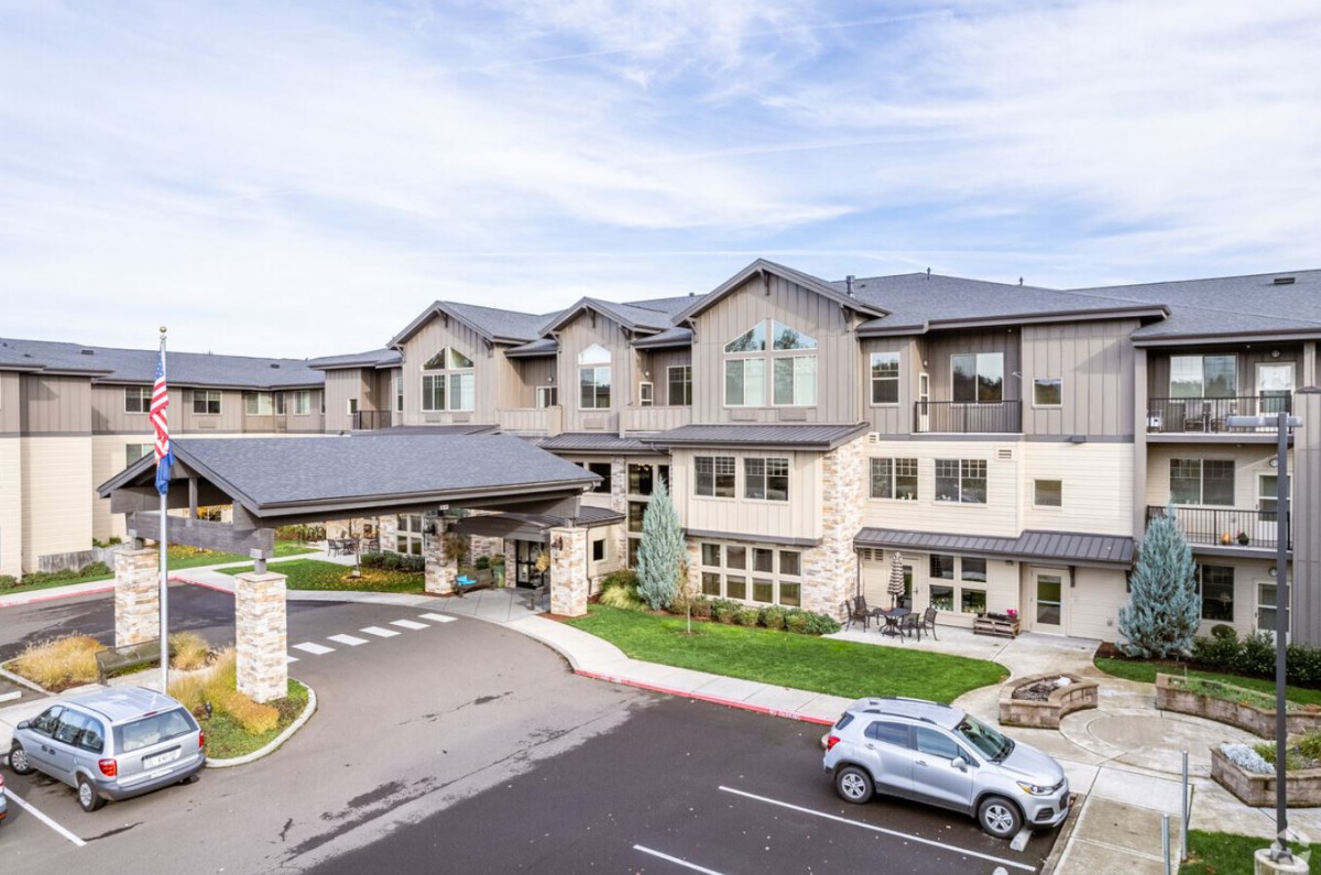 A modern residential building with a parking area in front.