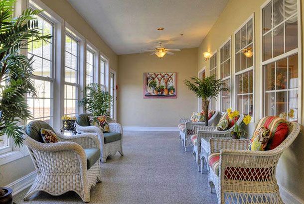 A bright and cozy sunroom featuring wicker furniture and lush plants.