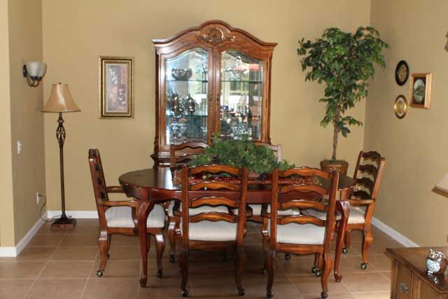 A classic dining room setup with a wooden table, matching chairs, and a display cabinet.