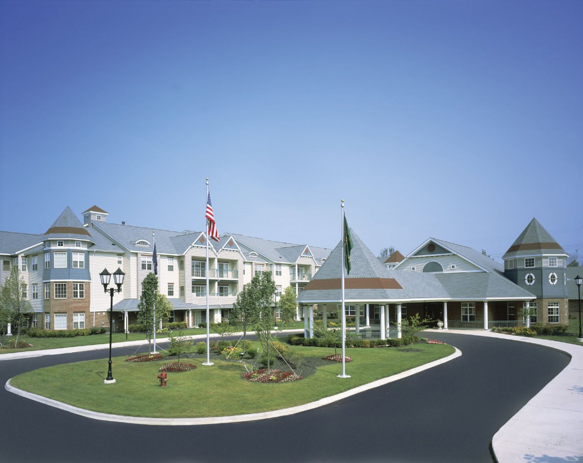 A large building with a circular driveway and flags at the entrance.