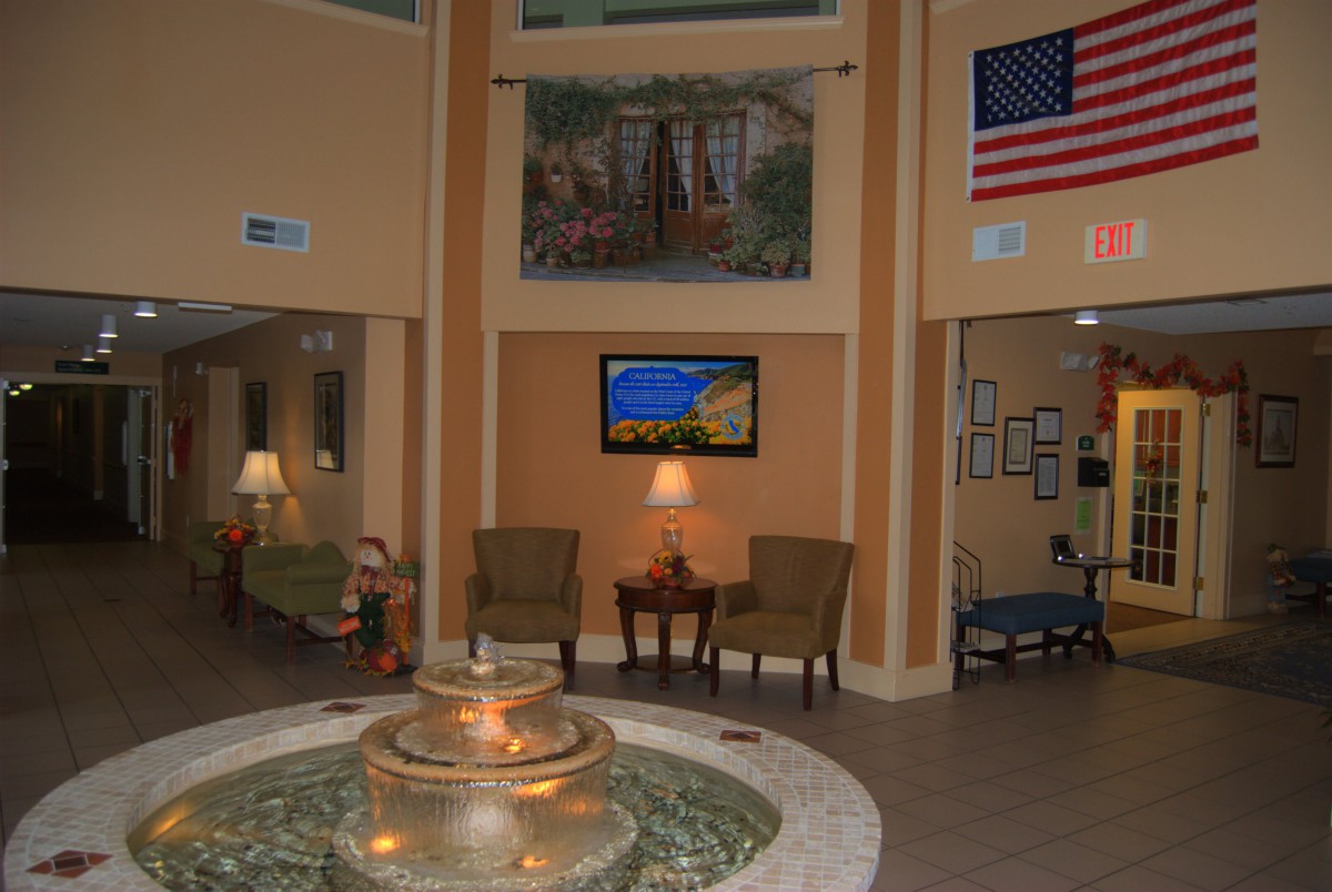 A welcoming lobby features a central fountain, chairs for seating, and an American flag on display.