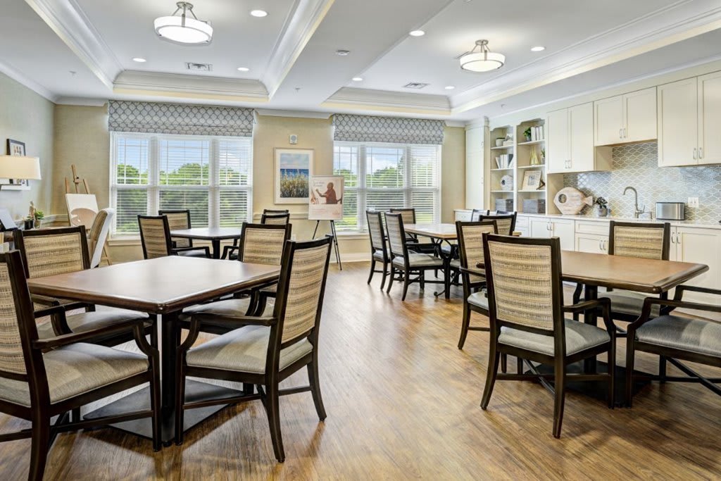 A bright and modern dining room with neatly arranged tables and chairs, featuring large windows and stylish lighting.