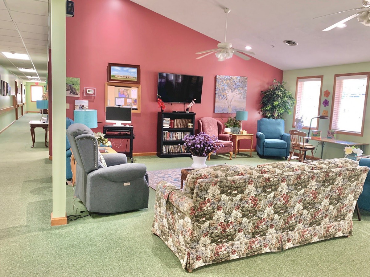 A cozy living room with colorful armchairs and a floral sofa facing a television.