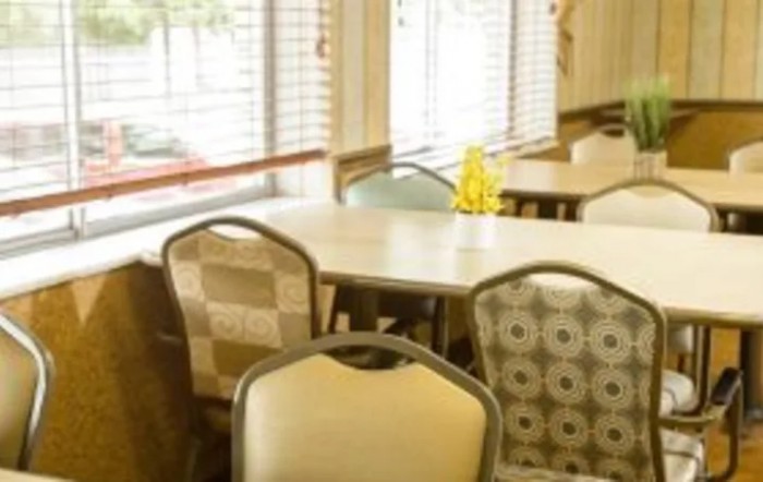 A cozy dining area with tables and chairs near large windows.