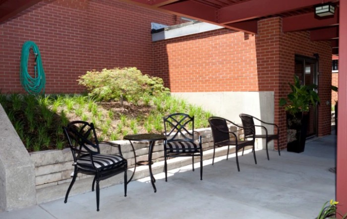 An outdoor patio area with chairs and a table against a brick wall.