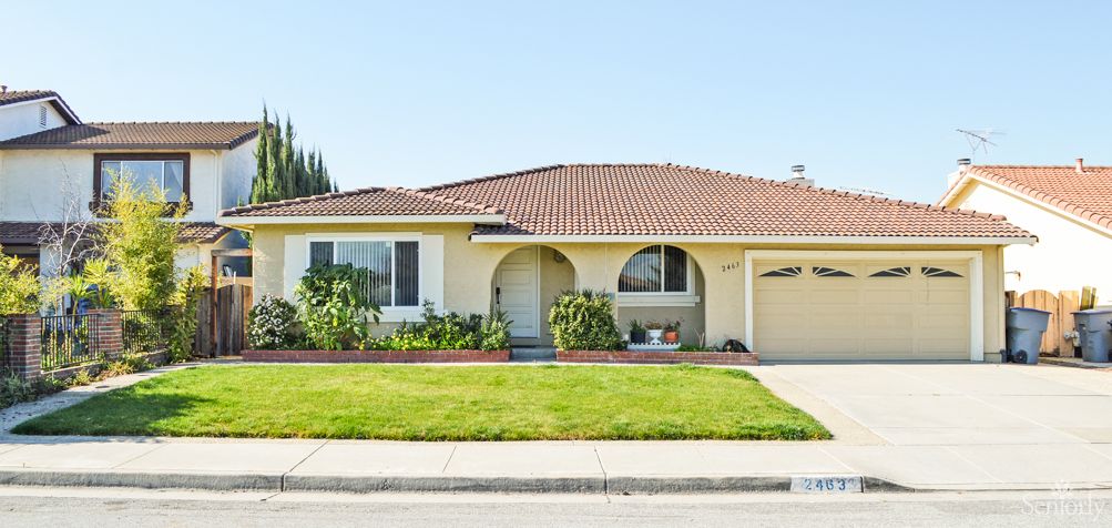 A suburban single-story house with a well-maintained lawn and garden.