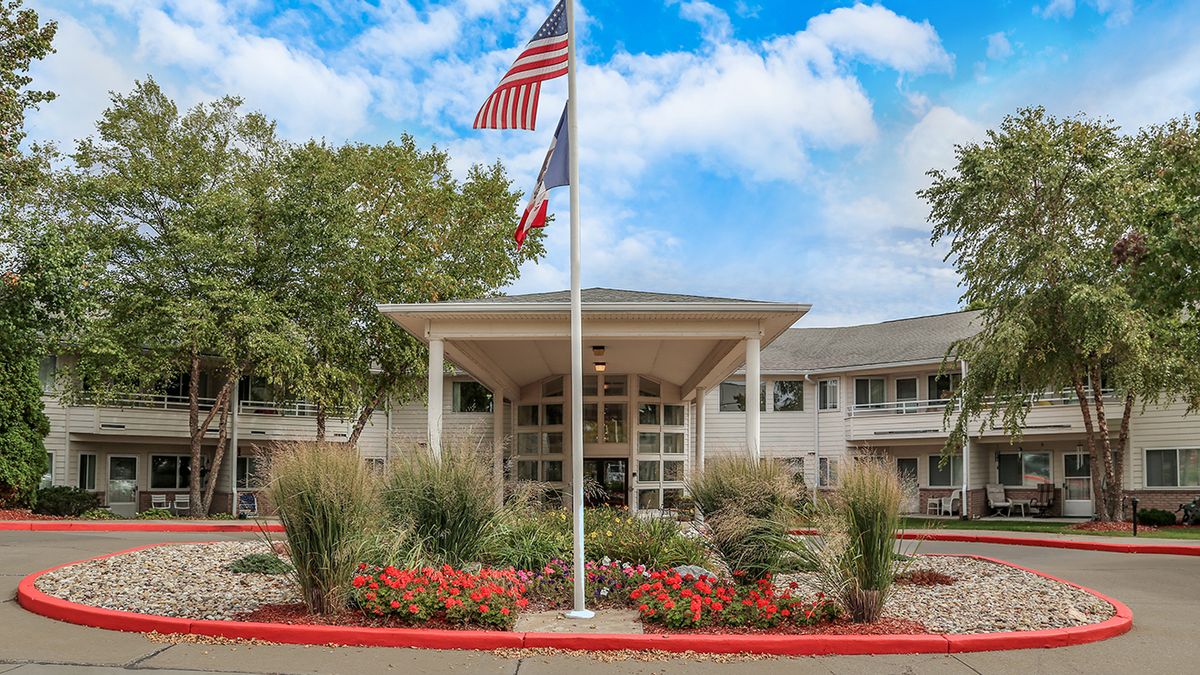 A well-maintained building entrance with flags and landscaped garden.