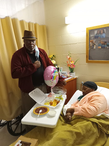 A visitor brings joy and celebration to a patient in a hospital room, complete with a balloon and a meal.
