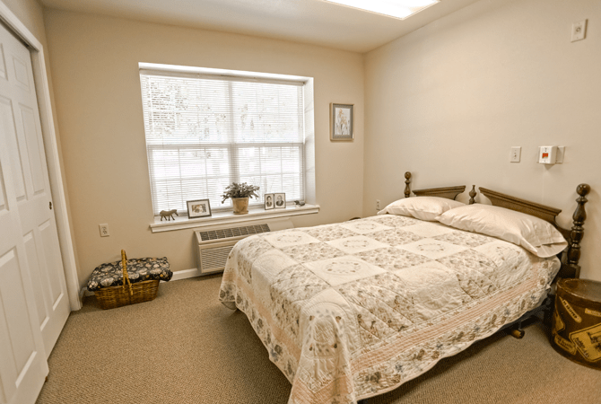 A cozy bedroom with a neatly made bed and natural light coming through the window.