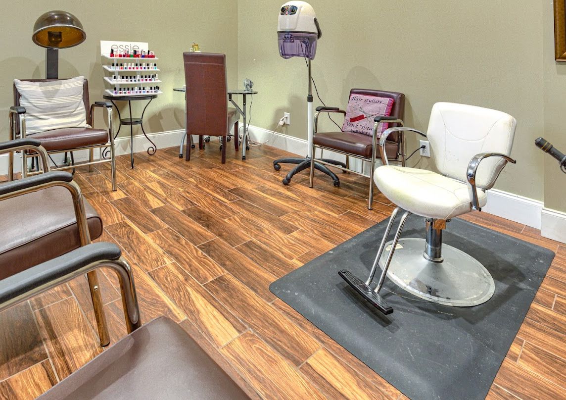 A stylish and well-equipped beauty salon with modern chairs and hardwood flooring.