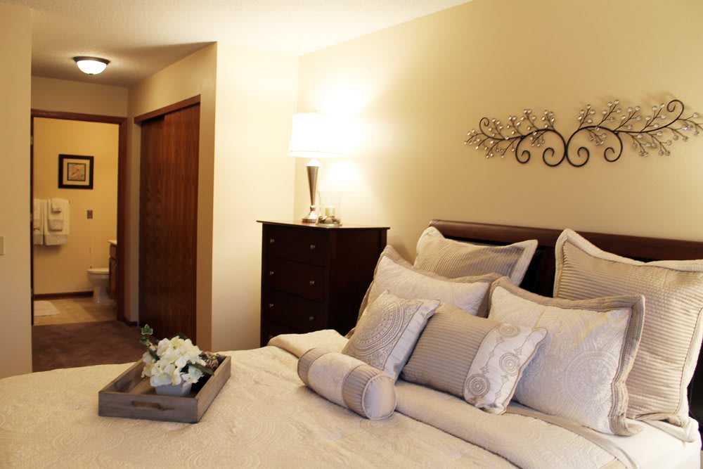 A cozy bedroom with a neatly made bed, decorative pillows, and elegant lighting.