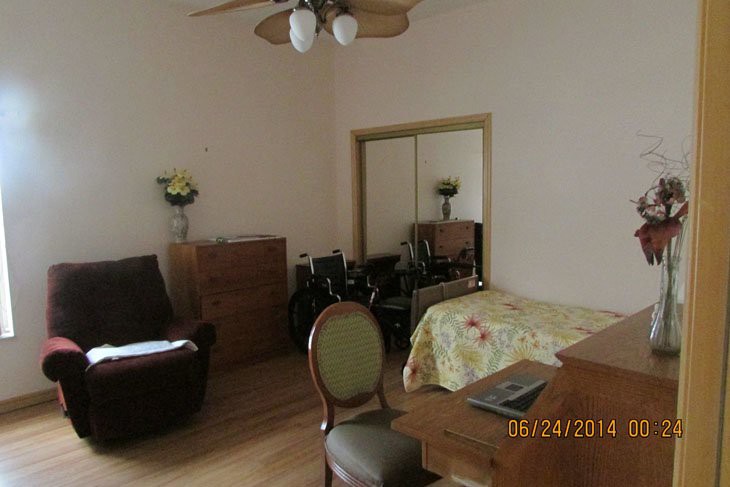 A bedroom with various furnishings, including a bed, chair, dresser, and mirror.