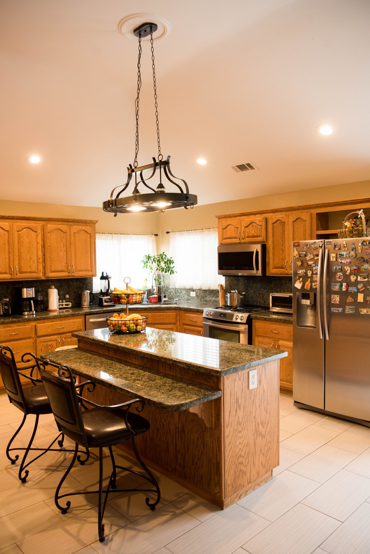 A modern kitchen with wooden cabinets, a granite island, and stainless steel appliances.